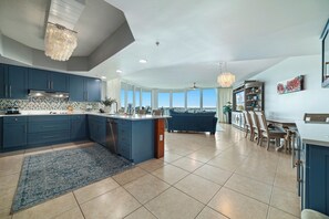 A spacious kitchen with a large island, dark blue cabinets, and a view to the outside.