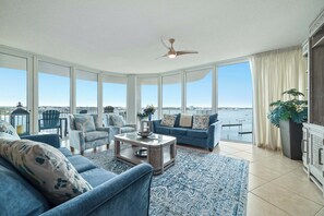 Un salon spacieux doté d’une grande baie vitrée, d’un ventilateur de plafond et offrant une vue sur l’eau.