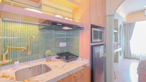 A modern kitchen with a built-in microwave, stainless steel sink, and wooden cabinets. - Chic Style Studio Apartment Grand Kamala Lagoon Bekasi (Bekasi)