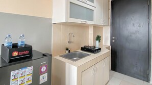 A compact kitchen with a refrigerator, a sink, and cabinets. - Basic Style Studio At Apartment Belmont Residence Puri (Jakarta)