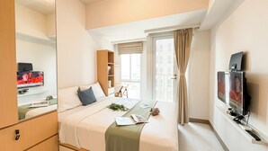 A hotel room with a bed, a desk, a television, and a window with curtains. - Studio Basic Apartment At Tokyo Riverside Pik 2 (Teluknaga)