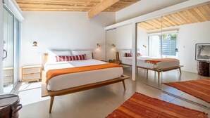 Een moderne slaapkamer met een groot bed, een houten plafond, een glazen deur en een grote spiegel.