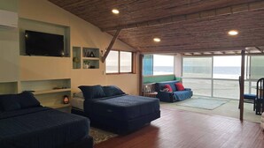 A modern living room with two sofas, a flat-screen TV, and a large window overlooking the beach. - Magnificent Suite with sea view on the third floor (Manglaralto)