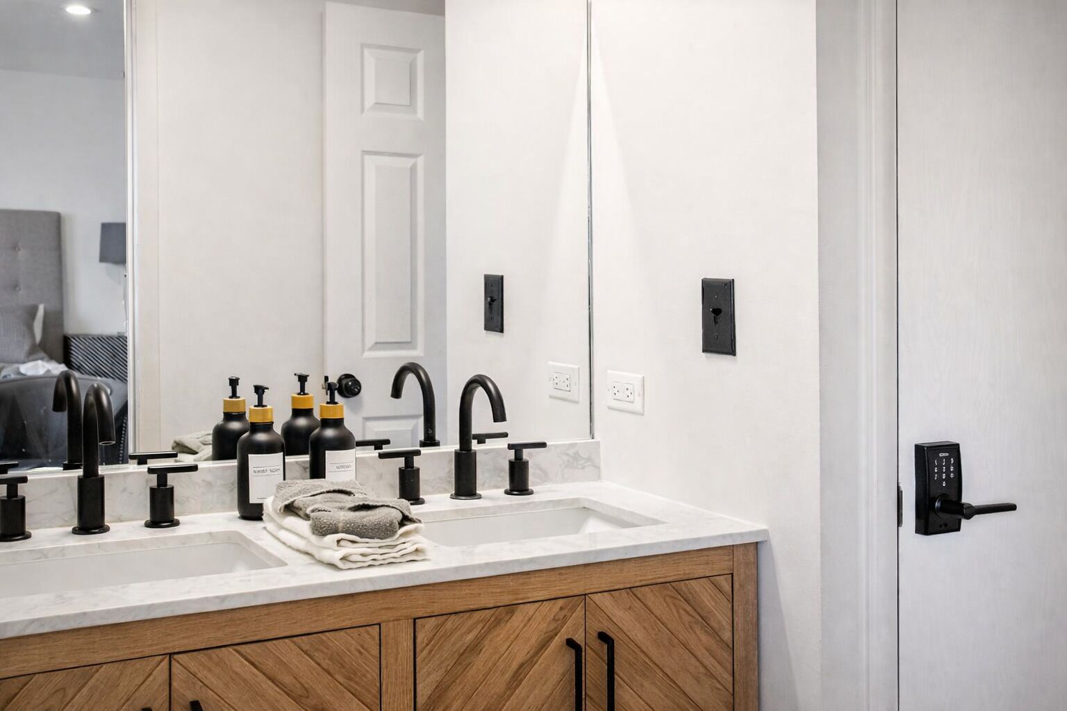 A modern bathroom with a double sink, black faucets, and a wooden cabinet.