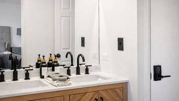 A modern bathroom with a double sink, black faucets, and a wooden cabinet.