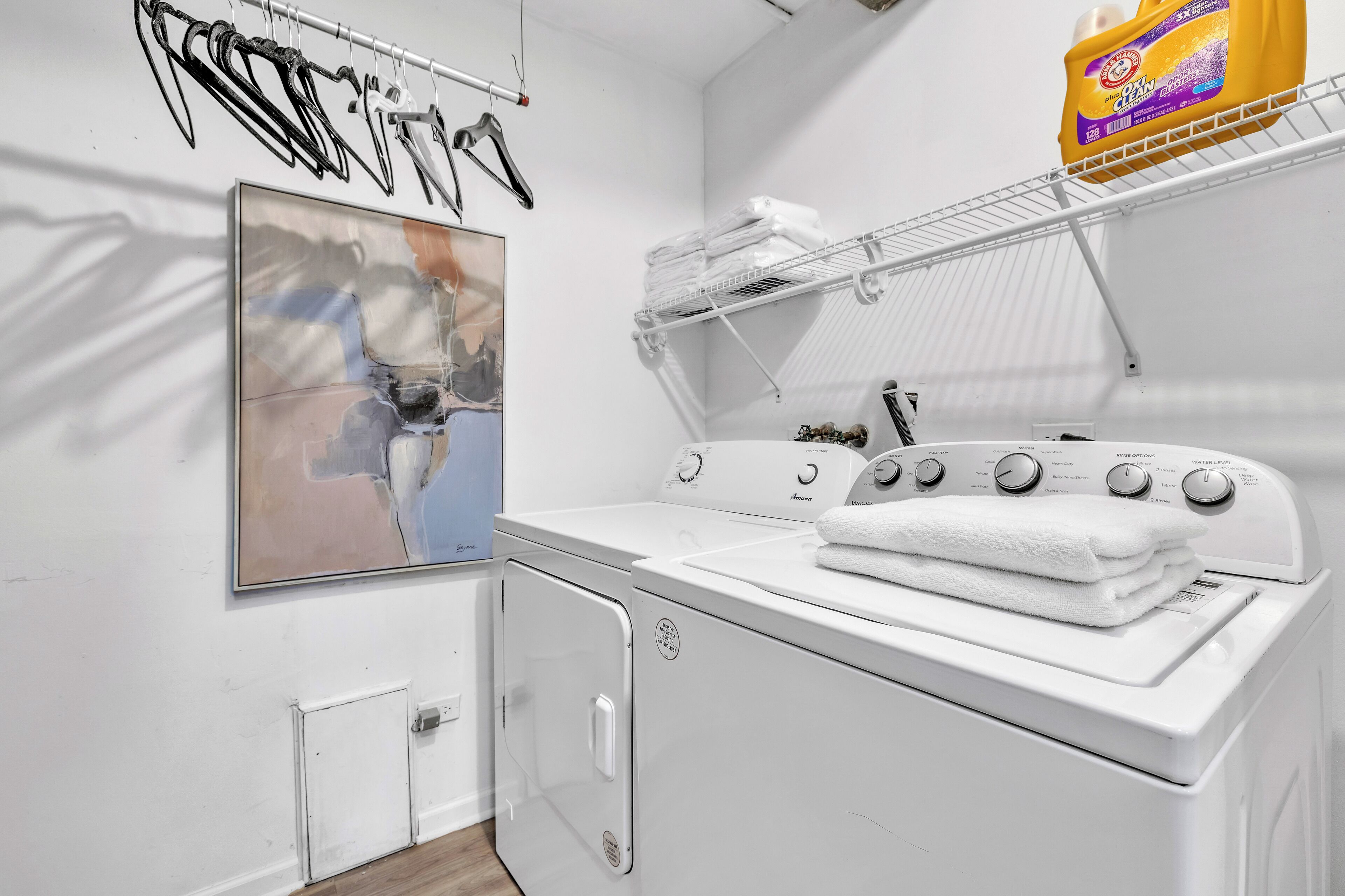 A laundry area with a washing machine, a dryer, and a rack with folded towels.