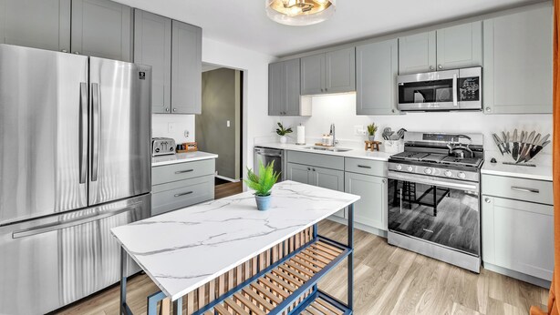 A modern kitchen with stainless steel appliances, a marble countertop, and grey cabinetry. - Modern Spacious  4BR Home Near Chicago • Sleeps 10 • Family & Pets Friendly (Westmont)