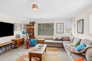 A living room with a sofa, coffee table, bookshelf, and a flat-screen TV.