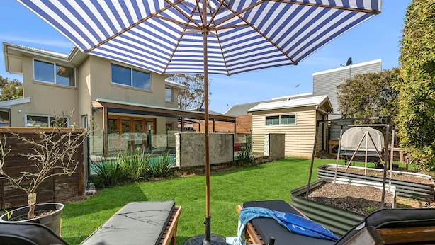 Un jardin avec un espace patio, une piscine et une maison.