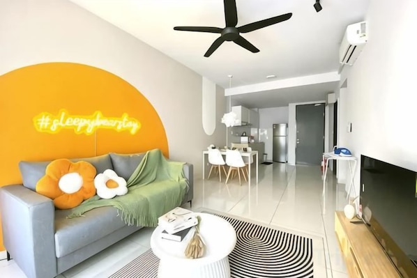 A modern living room with a sofa, coffee table, and a neon sign on the wall.
