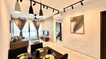 A modern dining area with a table set for four, a sofa, and a television in the background.