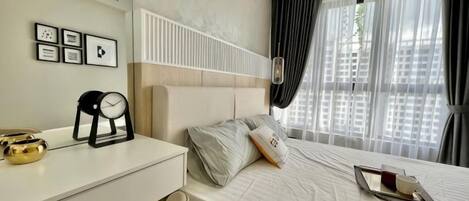 Habitación de hotel con cama, mesita de noche, reloj y cortinas.