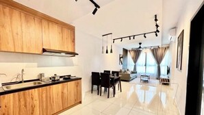A modern kitchen with wooden cabinets and a dining area with a table and chairs. - Gaia Residence, Gamuda Gardens Rawang by Sleepy Bear (Rawang)