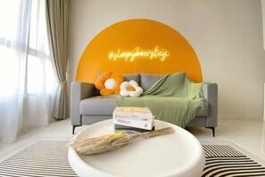 A living room with a sofa, a round coffee table, and a neon sign. - Gaia Residence, Gamuda Gardens Rawang by Sleepy Bear (Rawang)