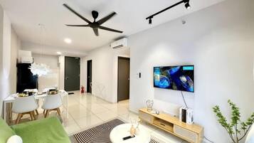 Una sala de estar moderna con un televisor de pantalla plana, un ventilador de techo y un comedor con sillas y una mesa.