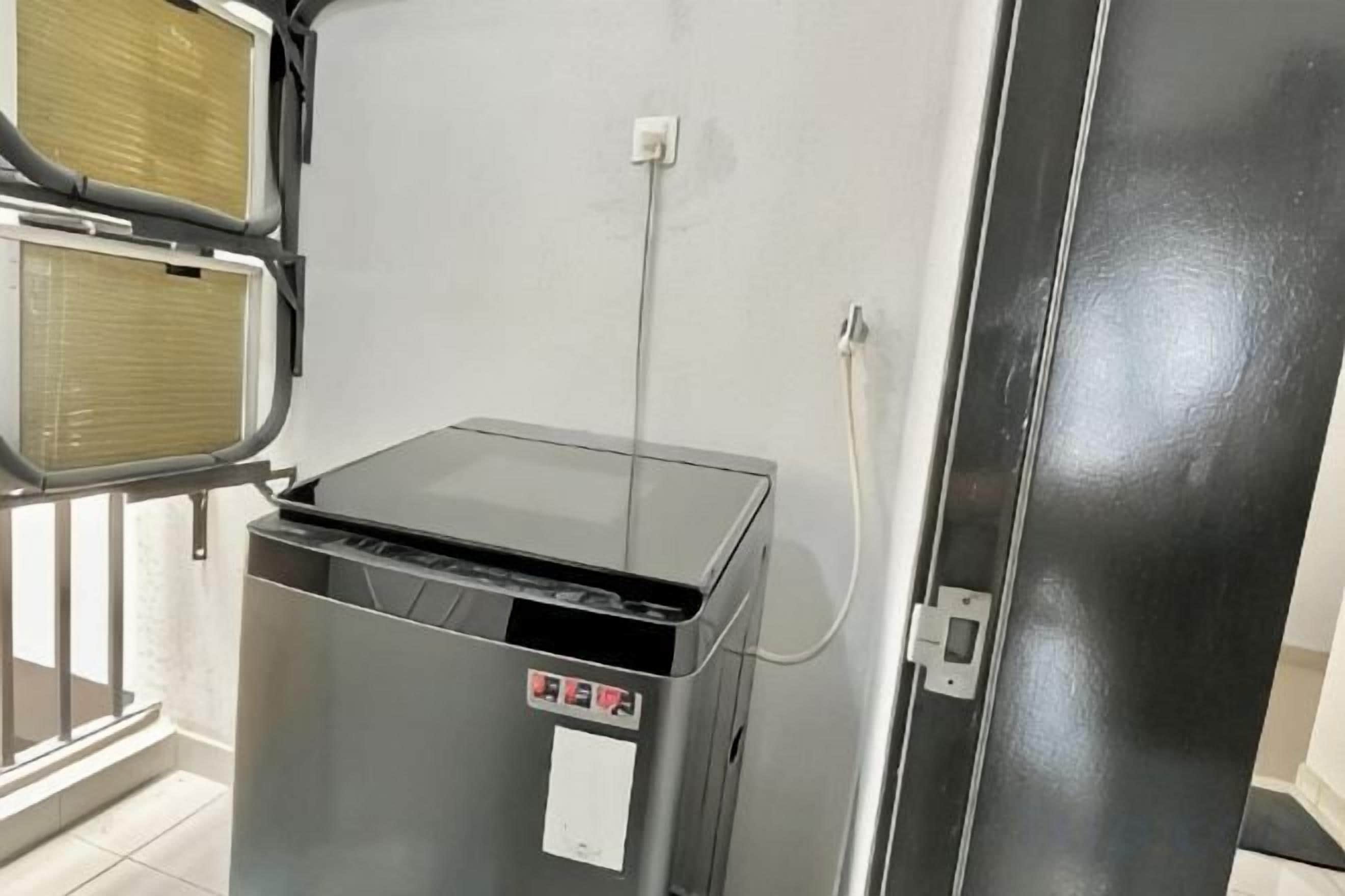 Una habitación con un calentador metálico cerrado, un panel de control y un enchufe en la pared.