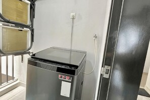 A room with a metallic, enclosed heater unit with a control panel and a power outlet on the wall. - Gaia Residence, Gamuda Gardens Rawang by Sleepy Bear (Rawang)