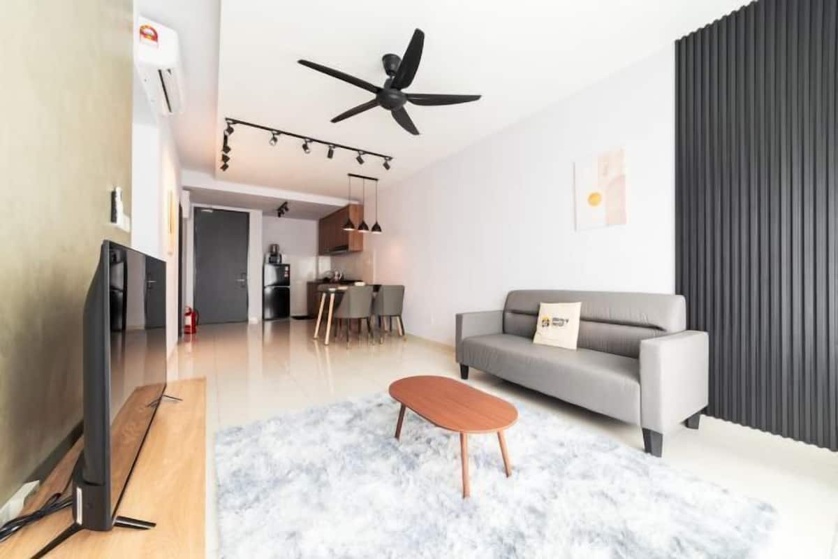 A modern living room with a flat-screen TV, a ceiling fan, a grey sofa, and a wooden coffee table.