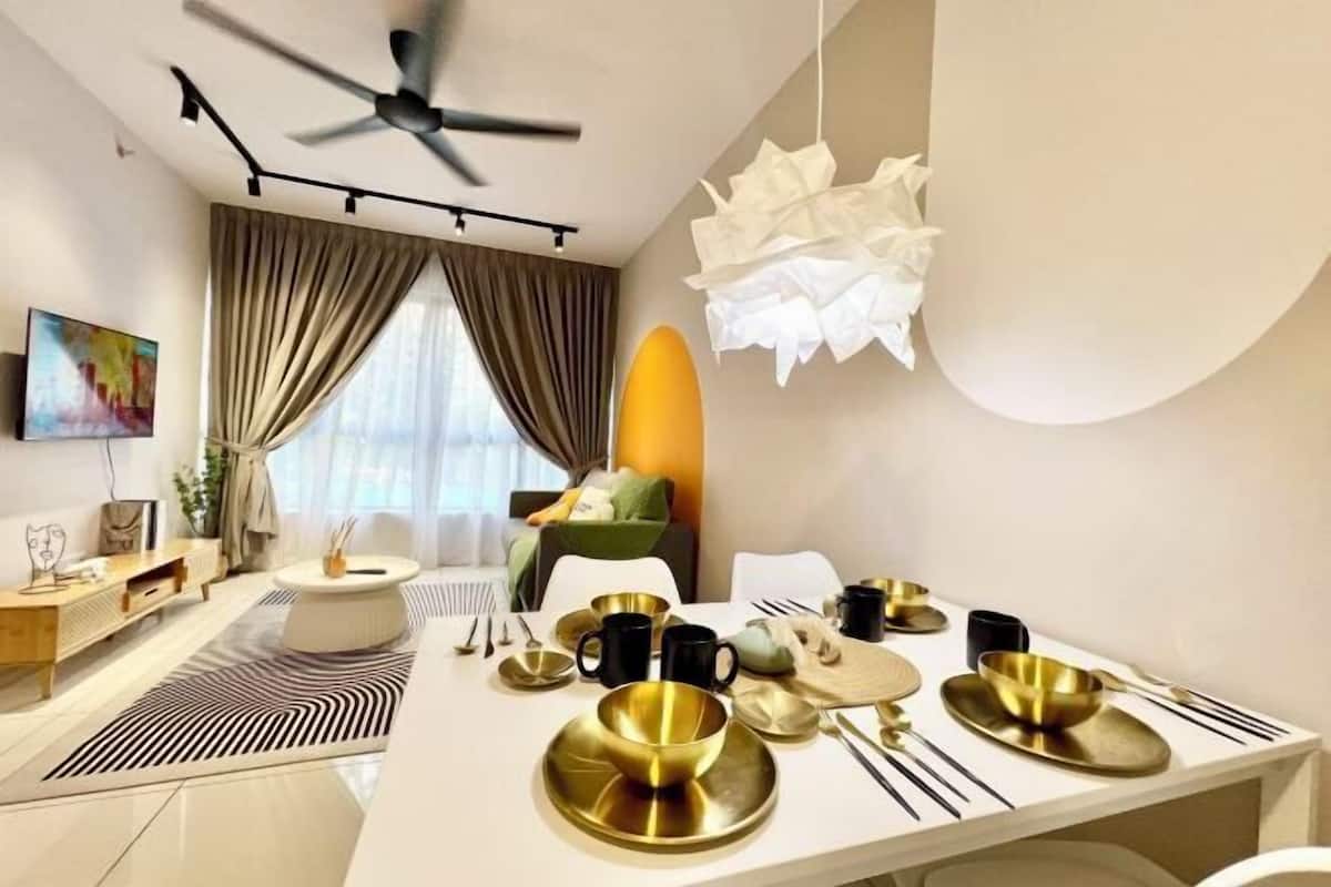 A modern dining area with a white table set for four, featuring gold and black tableware.
