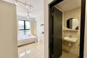 A hotel room with a bed, a bathroom with a sink and mirror, and a window with curtains.