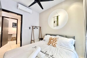 A bedroom with a bed, a ceiling fan, a wall-mounted circular light, and a door leading to another room. - Gaia Residence, Gamuda Gardens Rawang by Sleepy Bear (Rawang)
