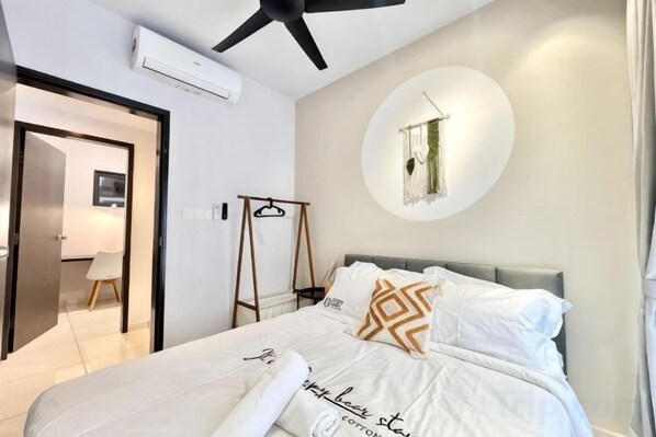 A bedroom with a bed, a ceiling fan, a wall-mounted circular light, and a door leading to another room. - Gaia Residence, Gamuda Gardens Rawang by Sleepy Bear (Rawang)