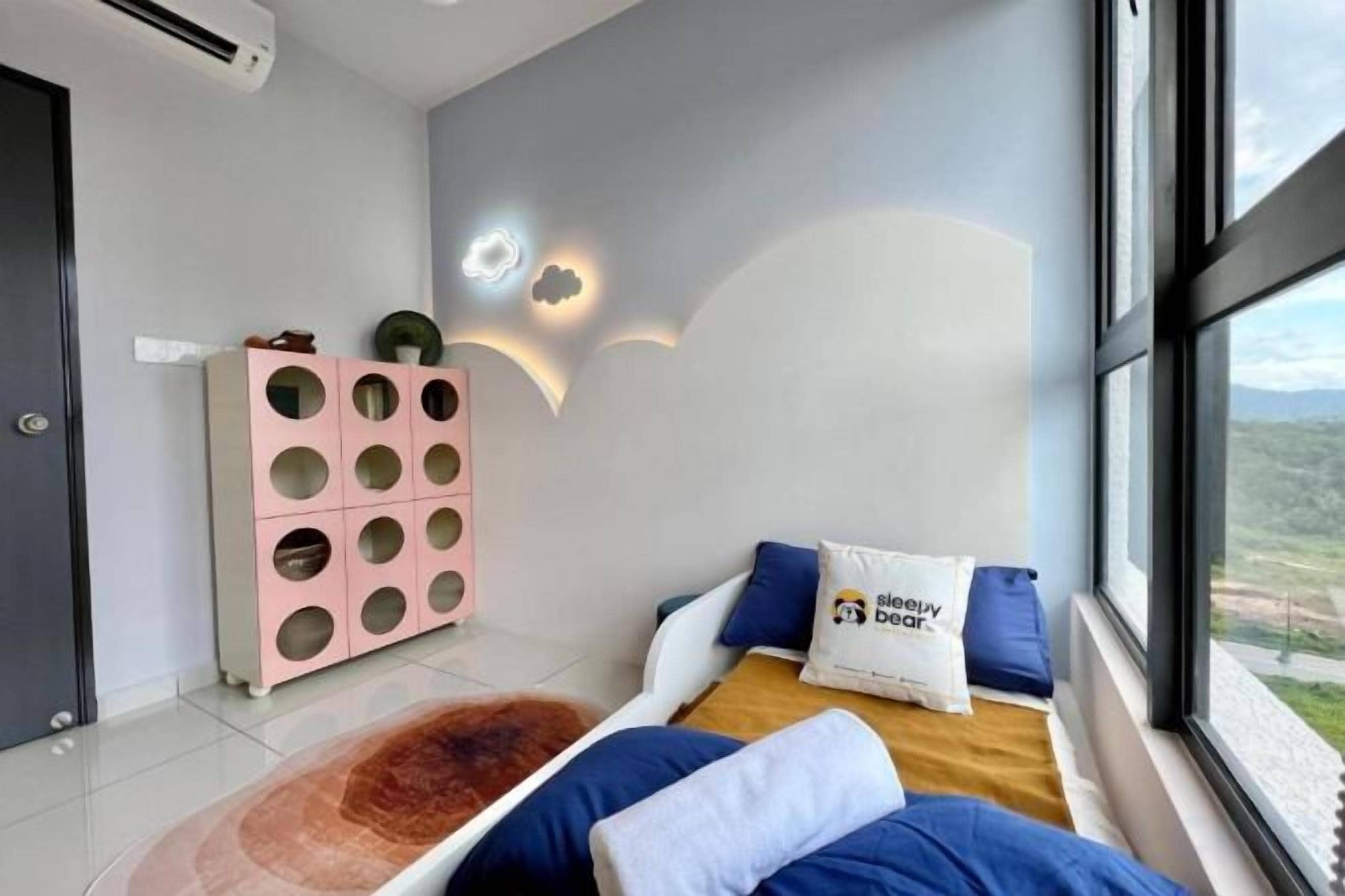 A bedroom with a bed, a window, and a wall-mounted light fixture.