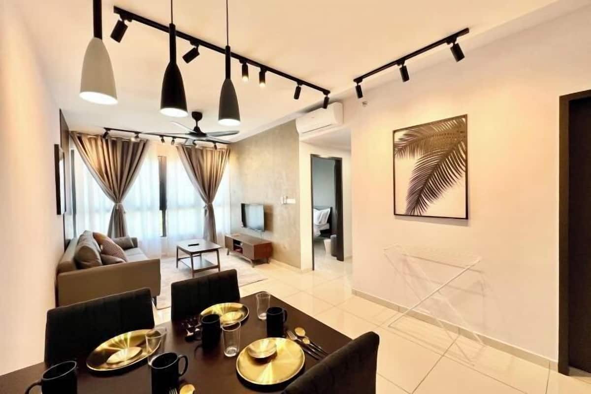 A modern hotel room with a dining area, a sofa set, and a large framed artwork on the wall.