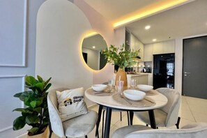A dining area with a round table, chairs, a mirror, and a potted plant. - Gaia Residence, Gamuda Gardens Rawang by Sleepy Bear (Rawang)
