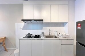 A modern kitchen with white cabinetry, a black range hood, a stainless steel refrigerator, and a sink. - Gaia Residence, Gamuda Gardens Rawang by Sleepy Bear (Rawang)