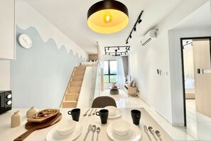 A modern kitchen with a dining table set for four, a staircase leading to a second floor, and a view of the outside. - Gaia Residence, Gamuda Gardens Rawang by Sleepy Bear (Rawang)
