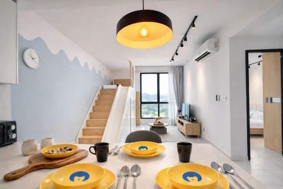 A modern living room with a dining area, featuring a staircase, a large window, and a minimalist design.