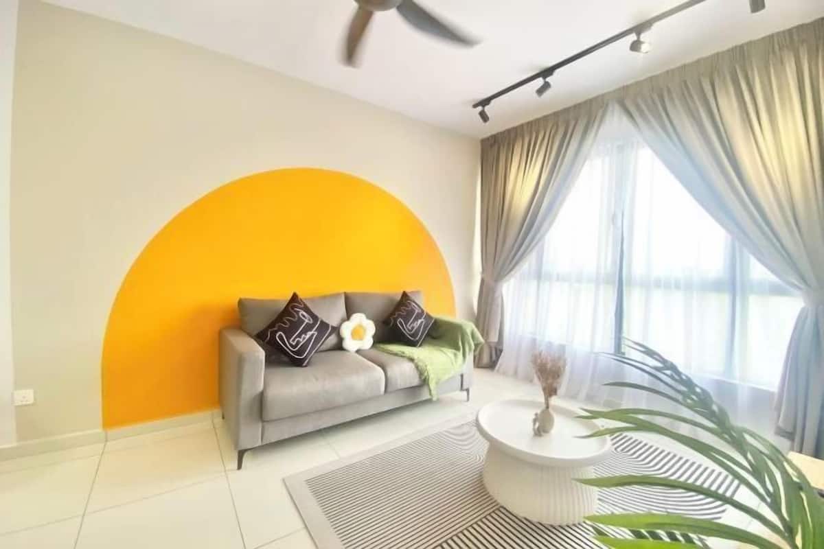 A modern living room with a sofa, a coffee table, a ceiling fan, and a large window with curtains.