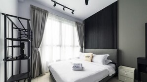 A modern hotel room with a bed, a nightstand, a desk, a black metal shelf, and a window with curtains. - Gaia Residence, Gamuda Gardens Rawang by Sleepy Bear (Rawang)