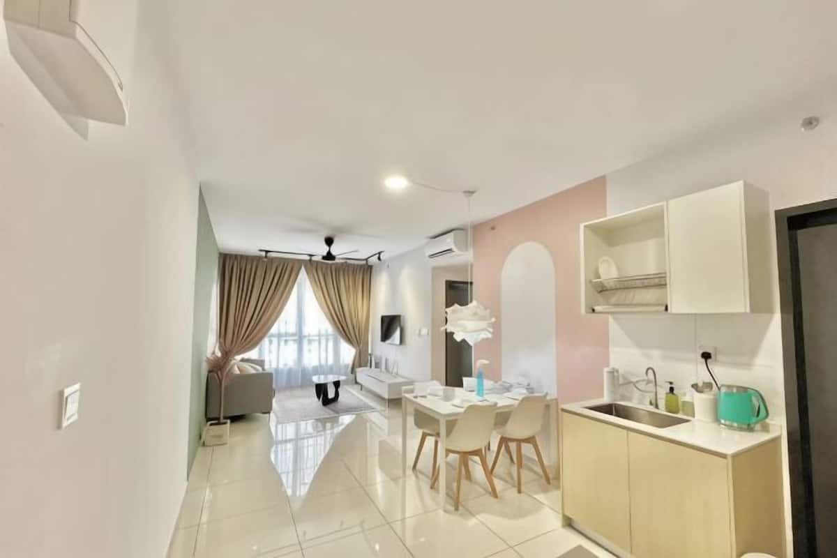 A modern kitchen with a sink, countertop, and cabinets. There is a dining area with a table and chairs.