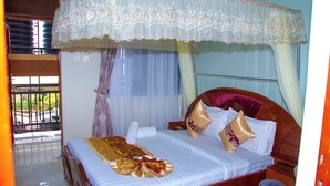 Uma cama com dossel, uma mesa de cabeceira e uma janela com cortinas.
