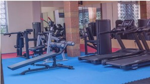 Uma academia com diversos equipamentos de exercício, incluindo aparelho de supino, máquinas de peso e esteiras.