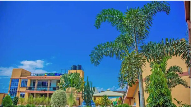 Hotel com vários andares e área de piscina, cercado por vegetação exuberante e palmeiras.