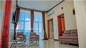 Sala de estar com dois sofás, uma mesa de centro e uma janela grande com cortinas.