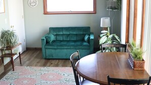 Un comedor con una mesa de madera, sillas, un sofá verde y un ventilador de techo.