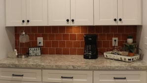 Una cocina con armarios blancos, una cafetera y un letrero que dice 'Coffee and Friends'.