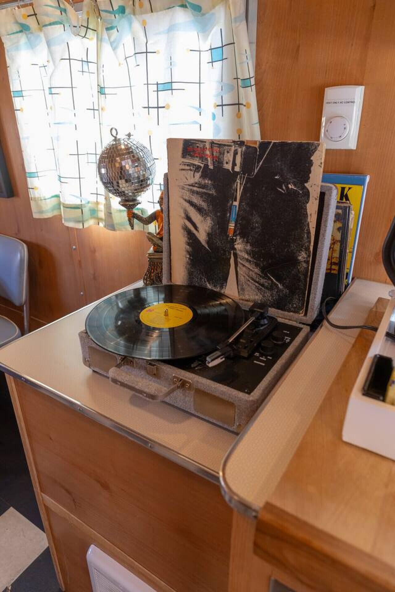 Una habitación con escritorio de madera, tocadiscos de vinilo y ventana con cortinas.