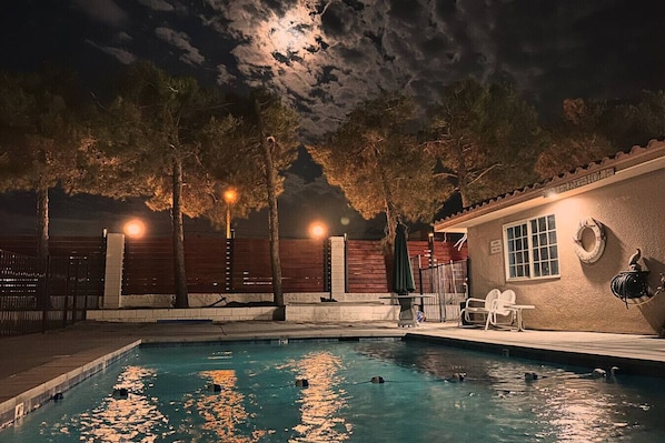 Una piscina con árboles y un edificio al fondo.