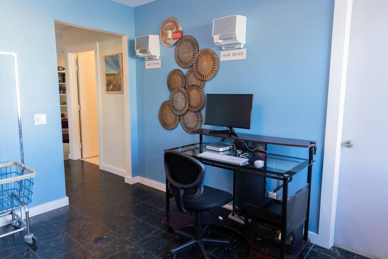 A room with a desk, computer, and two hair dryers labeled on the wall.
