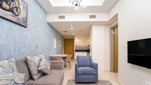 A modern living room with a sofa, armchair, and a flat-screen TV. - Helnan Royale (Dubai)