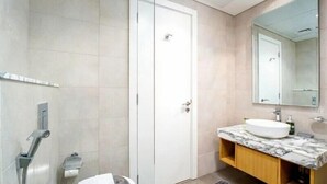 A modern bathroom with a white door, a marble sink vanity, and a large mirror. - Helnan Royale (Dubai)