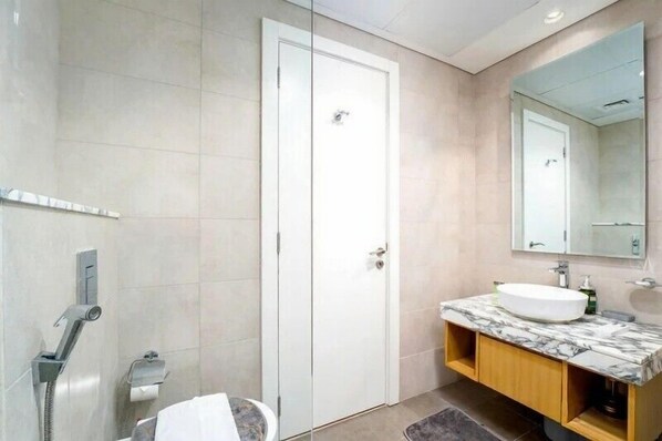 Une salle de bain moderne avec une porte blanche, un meuble-lavabo en marbre et un grand miroir.