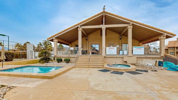 Un espacio cubierto al aire libre con piscina, jacuzzi y sillones de descanso.