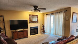 Una sala de estar con chimenea, televisor, sofá y ventilador de techo.
