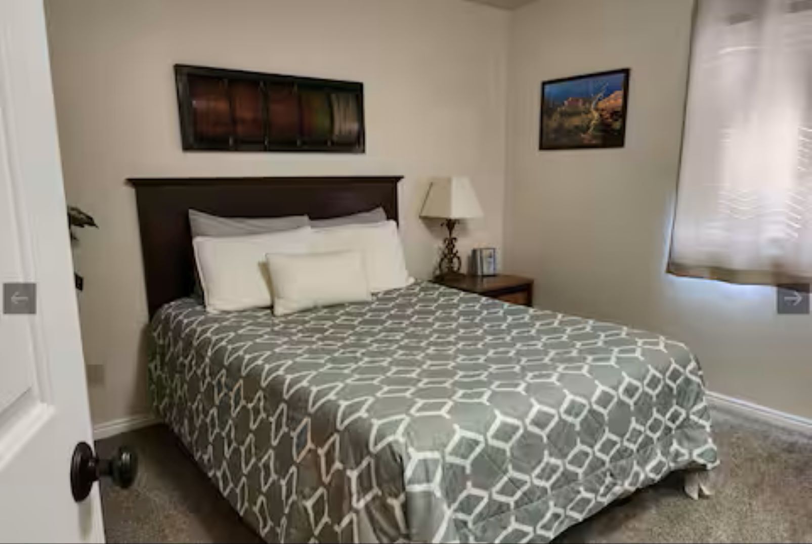 Een hotelkamer met een groot bed, een nachtkastje, een lamp en een schilderij aan de muur.
